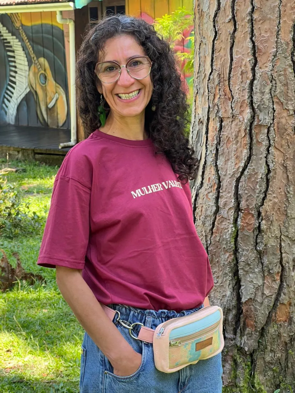 Mulher sorrindo com a camiseta Mulher Valente e pochete colorida