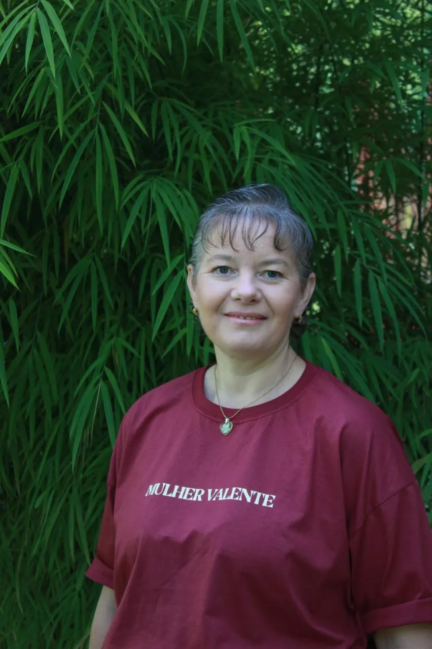 Mulher com a camiseta Mulher Valente em frente a folhagens