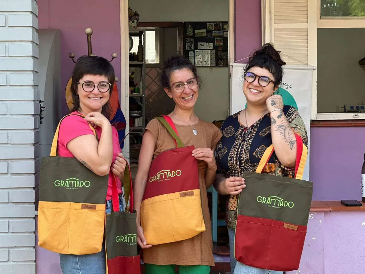 Cooperadas segurando ecobags produzidas para a Secretaria de Turismo de Gramado